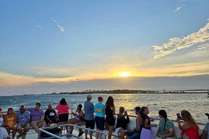 A group of people on a boat at sunset with a view of the horizon. 2