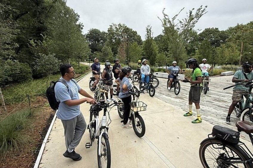 A group of people on bicycles on a paved path surrounded by greenery. 4