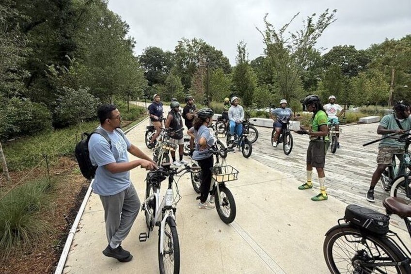 A group of people on bicycles gathered on a paved path in a park. 2