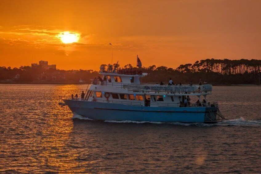 A boat with passengers, a sunset, and a city skyline in the background. 4