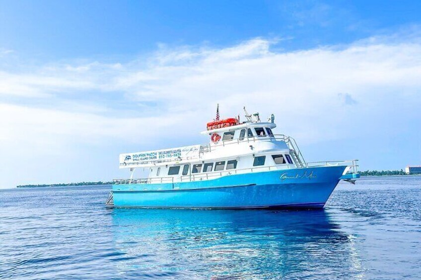 A blue and white boat with a lifebuoy and American flag on deck, sailing on calm waters. 1