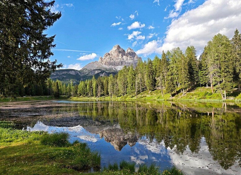 A mountain landscape with a lake reflecting trees and a clear sky. 1