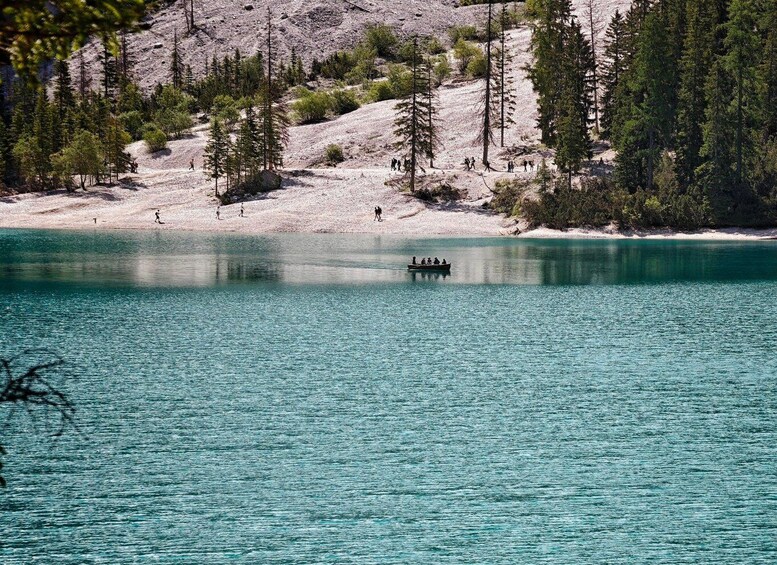 A turquoise lake surrounded by trees and a rocky hillside. 2