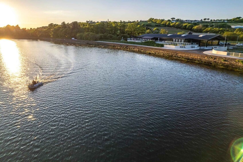 A river with a boat, a building with a covered area, and a hilly landscape in the background. 2