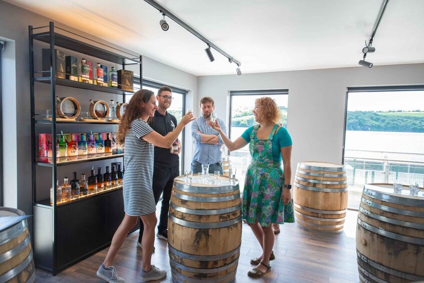 A group of people in a modern tasting room with wooden barrels and shelves of liquor bottles. 3