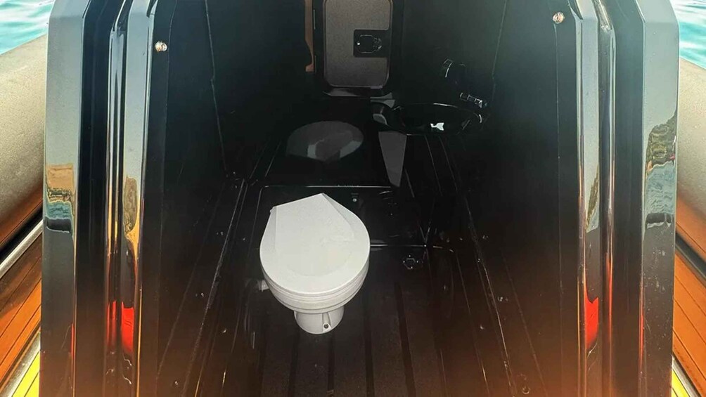 A compact, enclosed bathroom with a white toilet, a small sink, and a mirror. 3