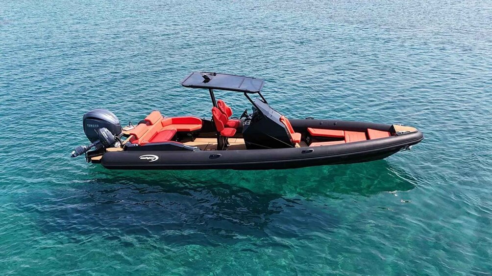 A black inflatable boat with red seats and a Yamaha outboard motor on clear blue water. 5