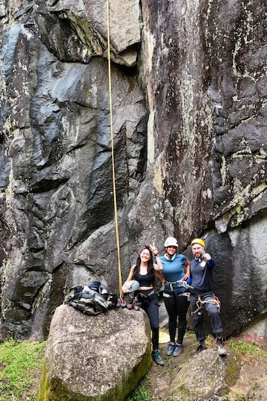 Three people climbing a rocky cliff with climbing gear and a rope. 4