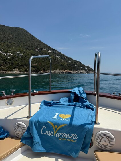 A boat with a blue towel and a 'I love Charter' sign, a metal railing, and a view of a coastline with houses. 3