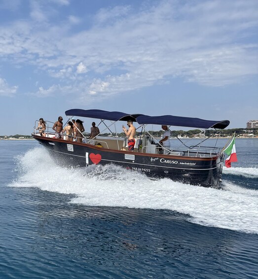 A boat named 'CARUSO' with a heart symbol and the text 'I love the sea' on its side, moving through the water. 1