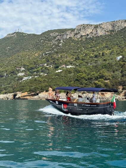 A boat with a blue canopy and a heart symbol on the side, moving through a body of water with a mountainous landscape in the background. 4