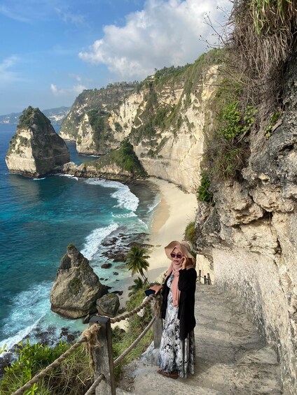 A coastal landscape with cliffs, a beach, and a person standing on a path. 2