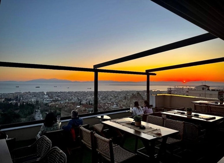A sunset view from a rooftop terrace with dining tables and chairs. 5