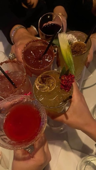 A group of people holding various cocktails with garnishes. 4
