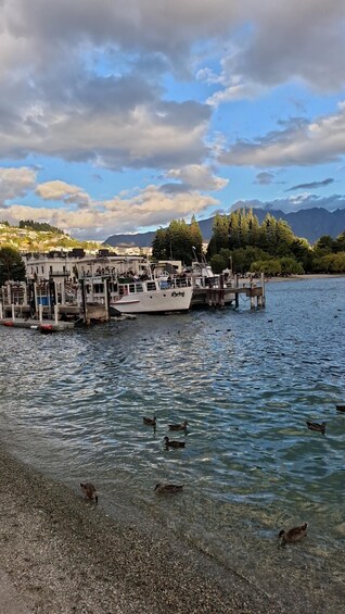 A boat docked at a pier with a mountainous backdrop and clear skies. 4