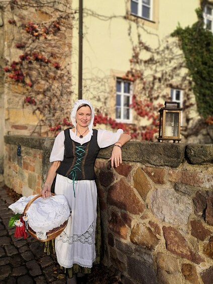 A person in traditional attire standing by a stone wall with a lantern. 4
