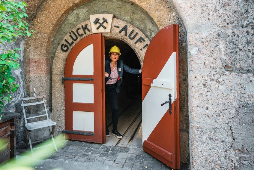 A person exiting a tunnel with a sign reading 'GLUCK AUF!' and a ladder beside the entrance. 3