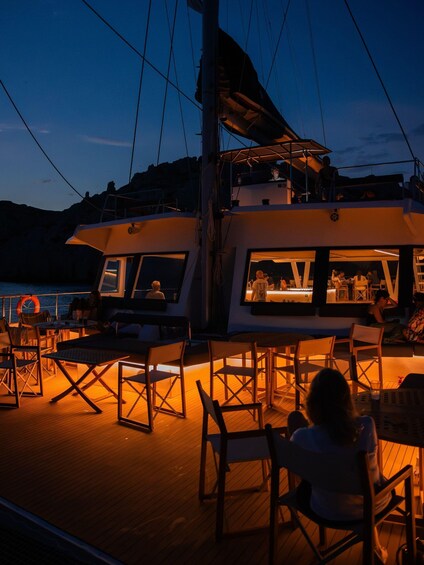 A yacht with outdoor seating and a bar area, docked at a marina. 3