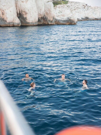People swimming in a body of water with rocky cliffs in the background. 2