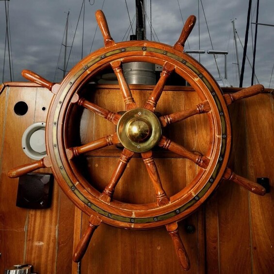 A wooden ship's wheel with brass fittings and a speaker mounted on the deck. 3