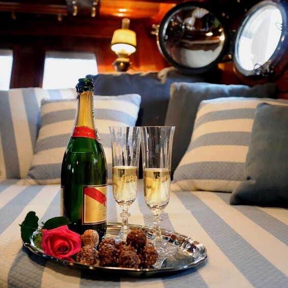 A bottle of champagne, two glasses, a rose, and chocolates on a tray. 5