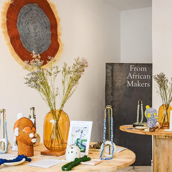 A table with various decorative items including a book titled 'From African Makers,' a woven basket, and several vases with dried plants. 3