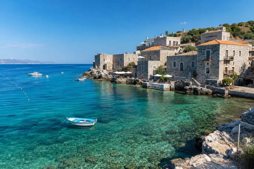 A coastal town with stone buildings, clear turquoise water, and anchored boats. 2