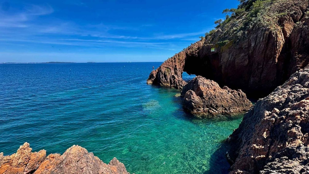 A coastal landscape with clear turquoise waters, rocky cliffs, and a distant shoreline. 1