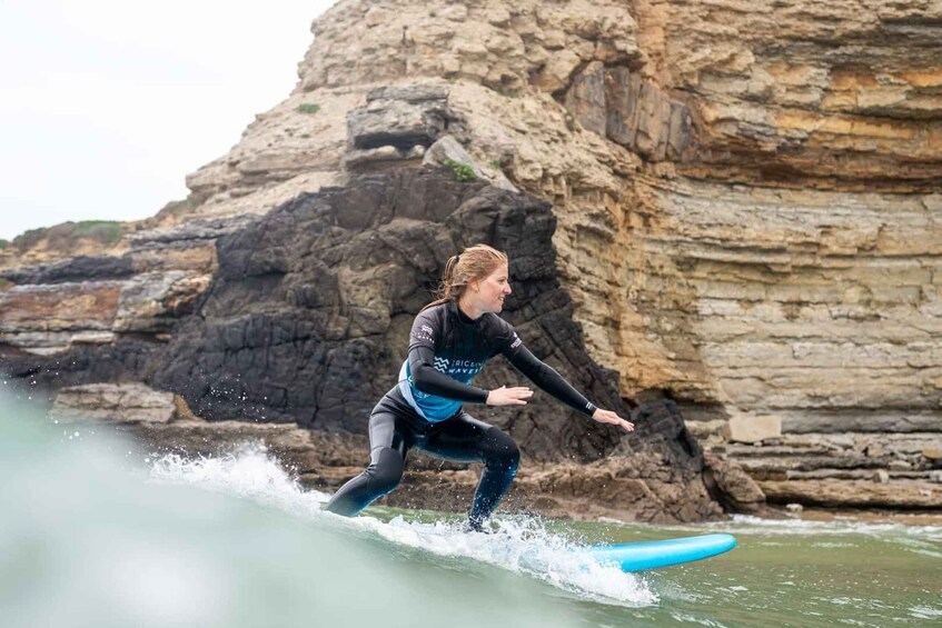 A person surfing on a wave near rocky cliffs. 2