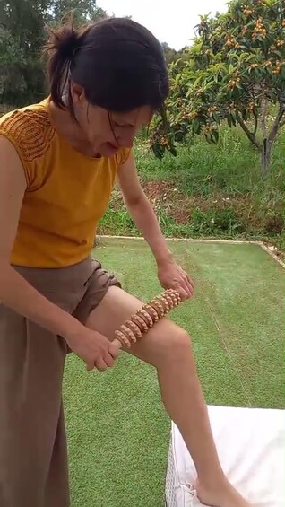 A person using a massage tool on their leg. 3
