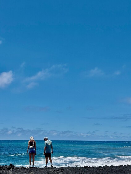 Zwei Personen laufen an einer felsigen Küste entlang, im Hintergrund das Meer. 5