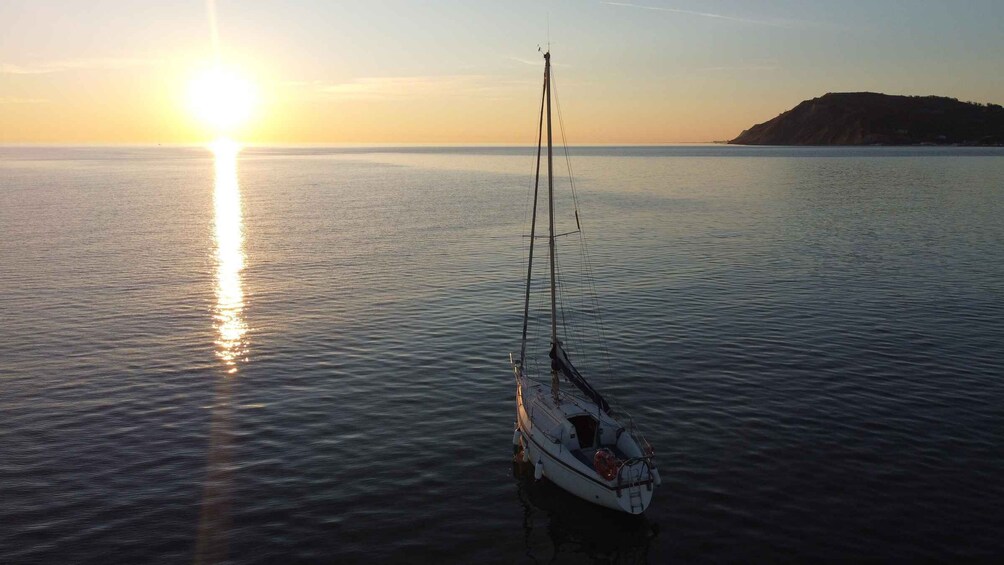 A sailboat anchored in calm waters during sunset. 3