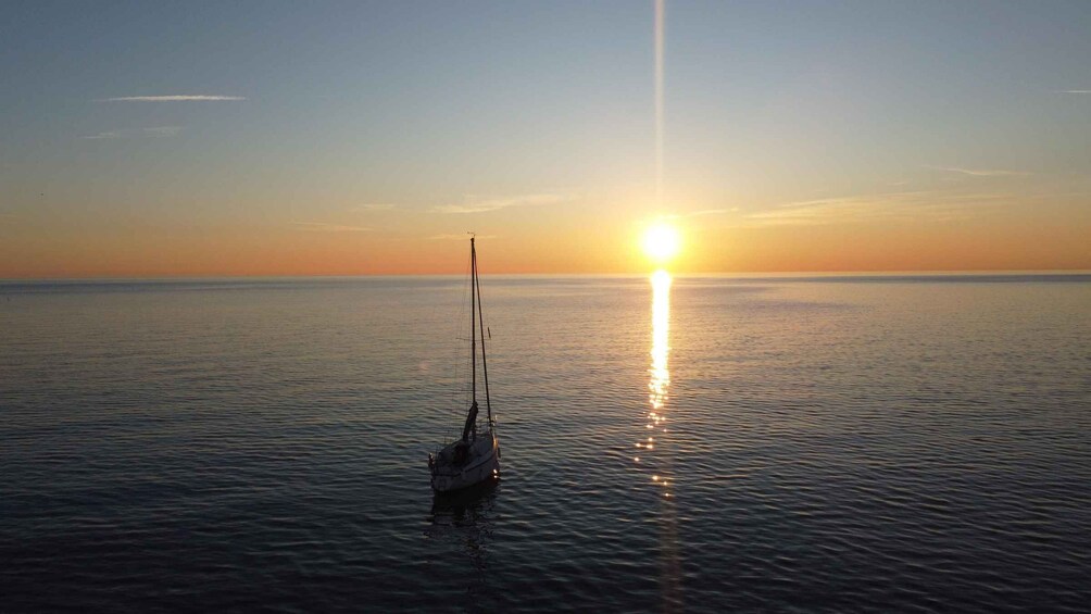 A sailboat on calm water during sunset. 1