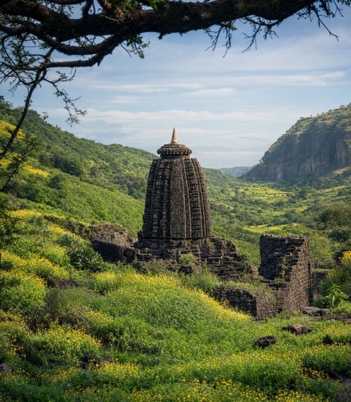 A stone structure with intricate carvings in a lush green valley. 1