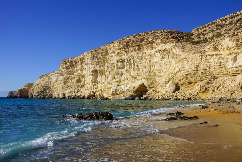 A coastal landscape with cliffs, clear blue sea, and a sandy beach. 2