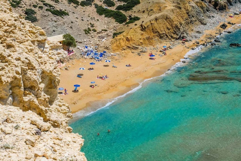 A coastal beach with clear turquoise waters, sandy shore, and rocky cliffs. 1