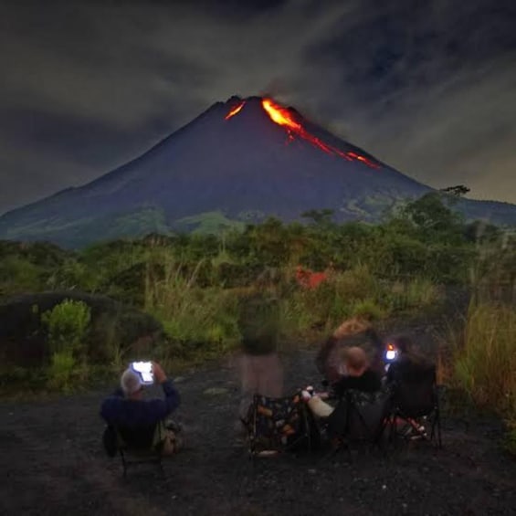 A volcano with lava flowing down its side, surrounded by vegetation. 4