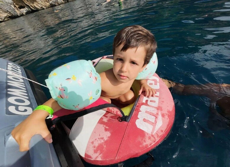A child on a paddleboard in a body of water with a boat nearby. 2