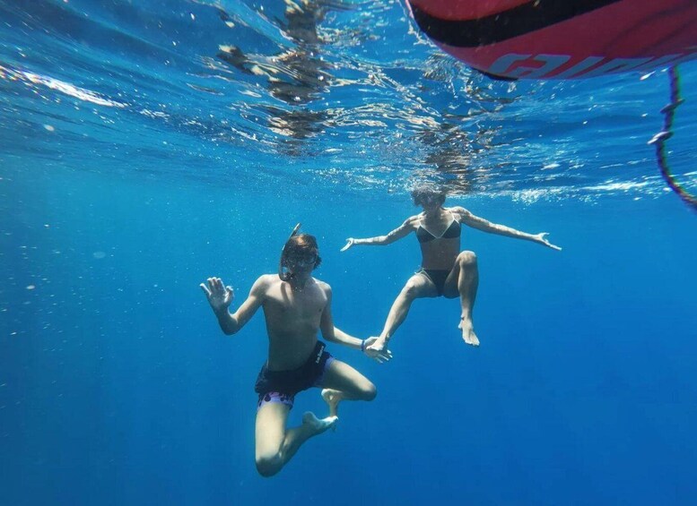 Two people swimming underwater in clear blue water. 5