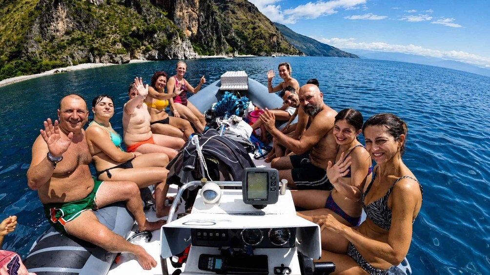 A group of people on a boat in a body of water with a mountainous coastline in the background. 1