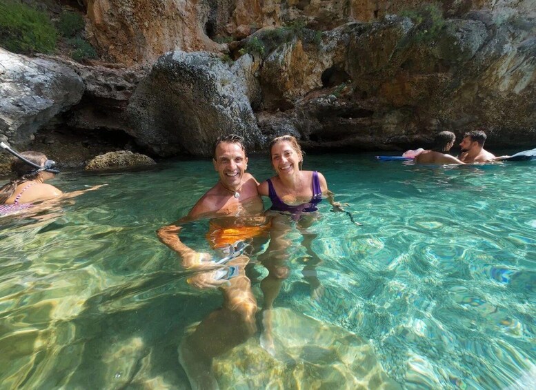 A couple in a clear pool with rocky cliffs in the background. 4