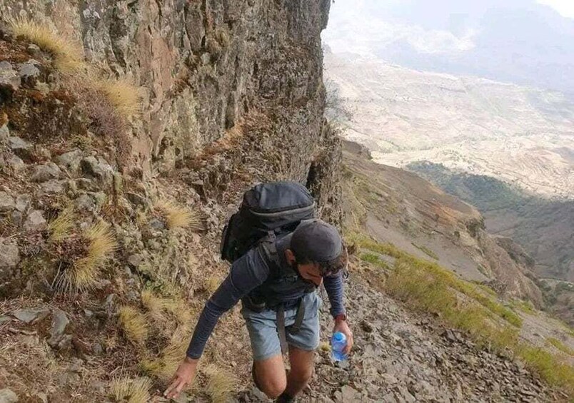 Un escursionista su un sentiero roccioso con uno zaino, immerso in un paesaggio montuoso. 2
