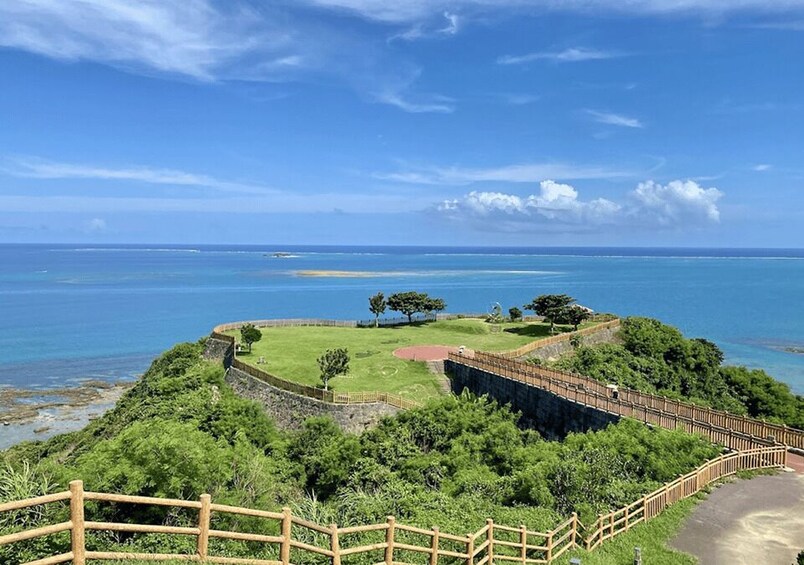 A coastal landscape with a wooden fence, a grassy area, and the ocean in the background. 4