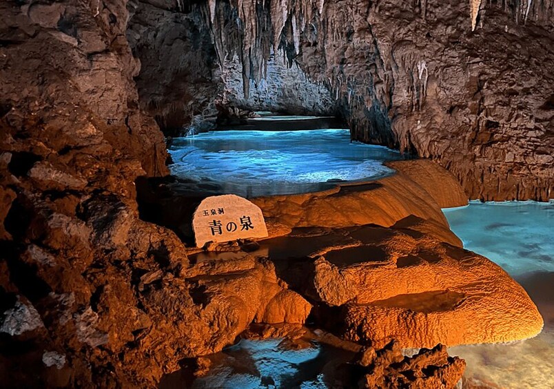 A cave with a water pool and a stone with Japanese characters. 1