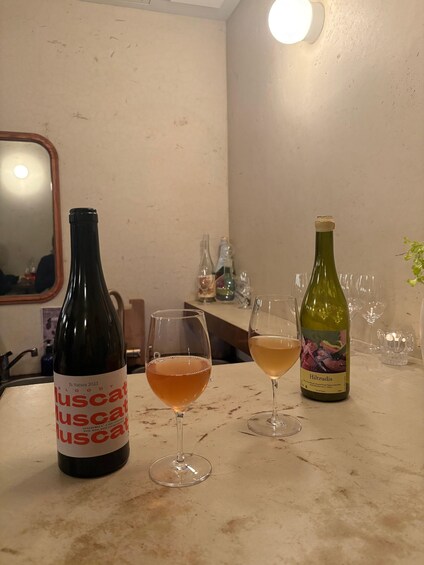 A bottle of 'BLOODY MUSCAT' wine and two glasses on a kitchen counter. 5