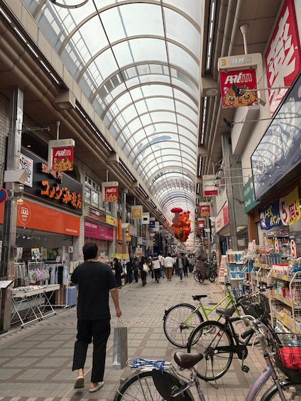 A busy indoor shopping area with a glass ceiling, various shops, and bicycles parked. 4