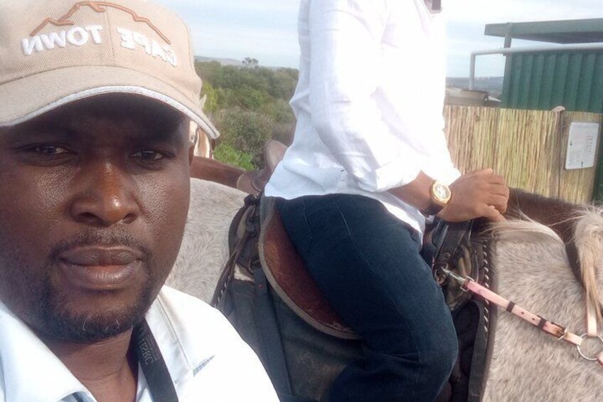 A person riding a horse with a pink lead rope, wearing a white shirt and a cap with 'TOWN' on it. 2