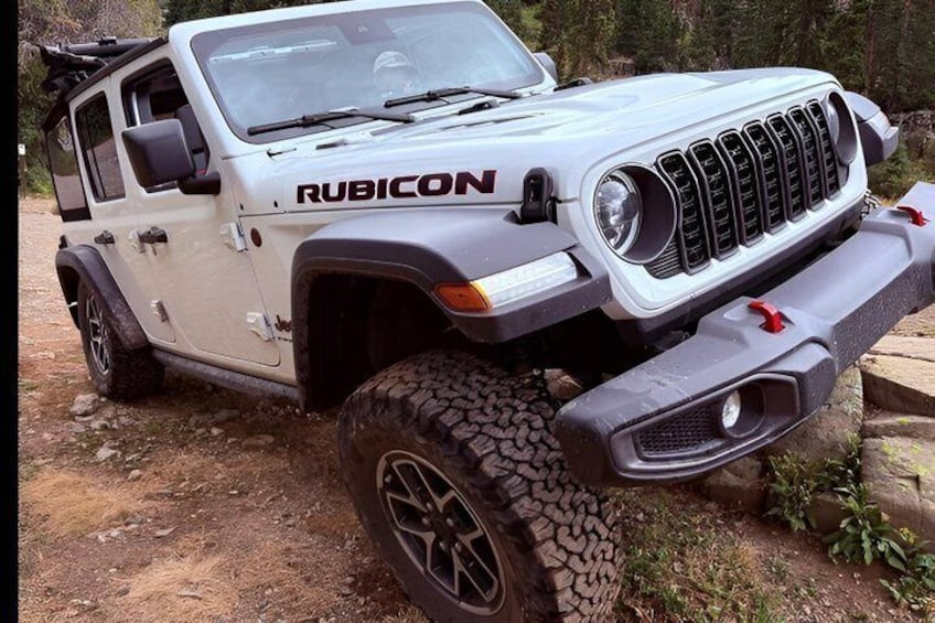 A white off-road vehicle with 'RUBICON' branding, large tires, and a rugged front bumper. 3