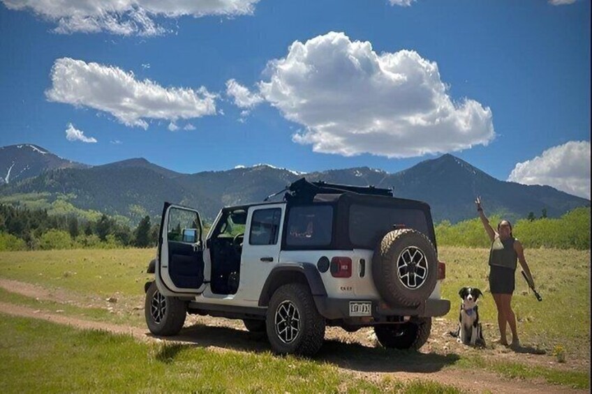 A white off-road vehicle parked on a dirt path with a mountainous landscape in the background. 4