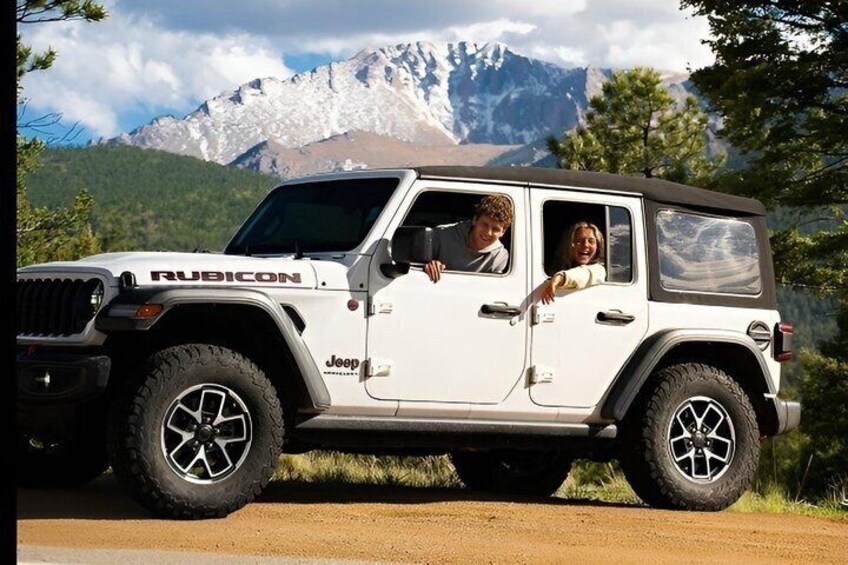 A white Jeep Rubicon parked on a dirt road with mountains in the background. 5